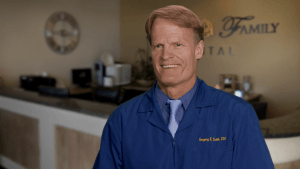 A man in blue shirt and tie standing next to counter.